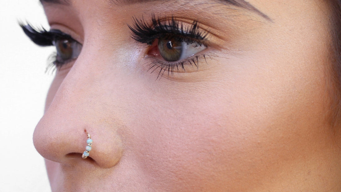 Close-up of a pierced nostril wearing a gold beaded nose ring