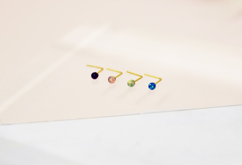 Four gold L-shaped nose studs with coloured crystals